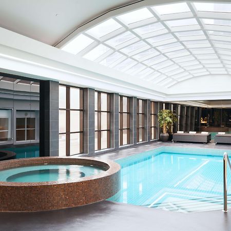 מלון Stamford Plaza מלבורן מראה חיצוני תמונה The photo shows an indoor swimming pool area. The pool is rectangular and has clear blue water, surrounded by a sleek, modern design. On one side, there is a round hot tub made of dark stone. Large windows line the walls, allowing natural light to fi