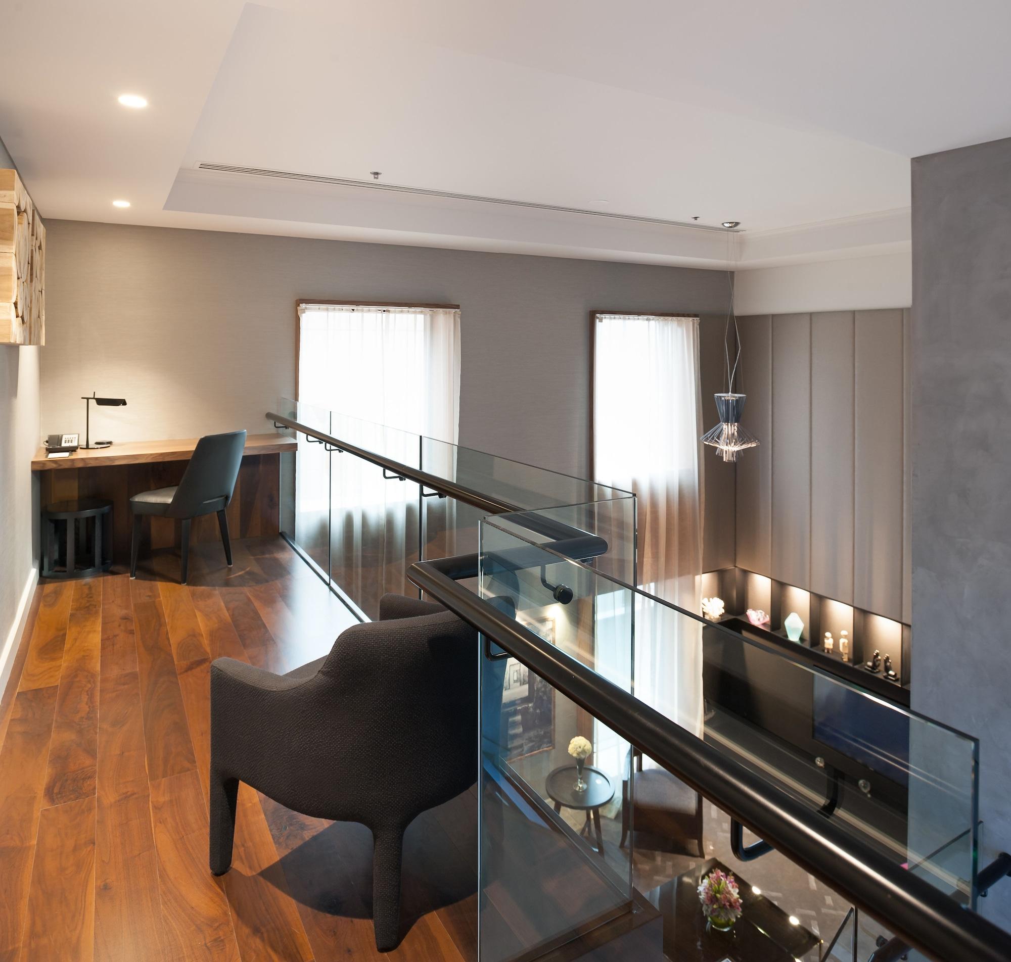מלון Stamford Plaza מלבורן מראה חיצוני תמונה The photo shows a modern interior space, featuring a second-floor balcony overlooking a lower level. The decor is stylish and minimalistic, with a combination of wooden flooring and neutral-colored walls. 

On the upper level, there is a small desk a