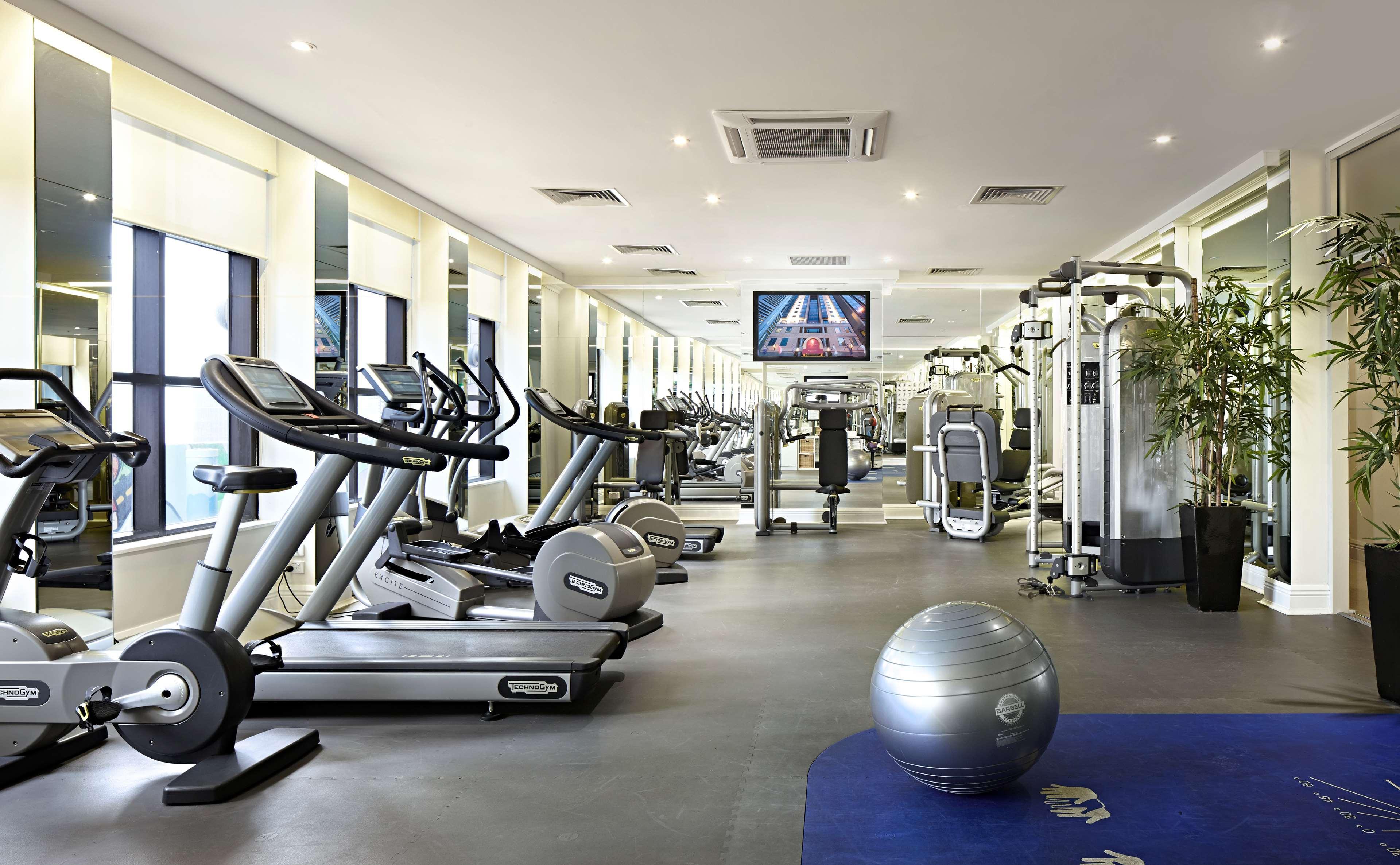 מלון Stamford Plaza מלבורן מראה חיצוני תמונה The photo shows a modern gym or fitness center. There are several exercise machines, including treadmills and elliptical trainers, positioned near large windows that allow natural light to flood the space. A television is mounted on the wall, likely 