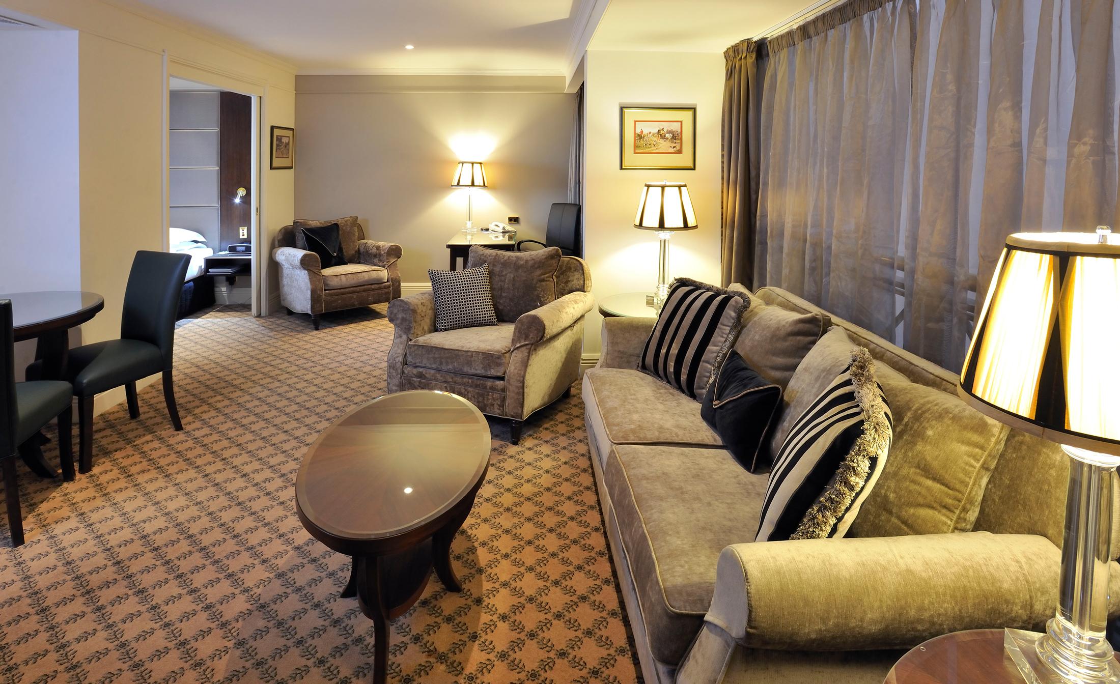 מלון Stamford Plaza מלבורן מראה חיצוני תמונה The photo shows a stylish and comfortable living area. It features plush seating, including a sofa with decorative cushions and a couple of armchairs. There's a circular coffee table in the center of the seating arrangement. The room has soft lightin
