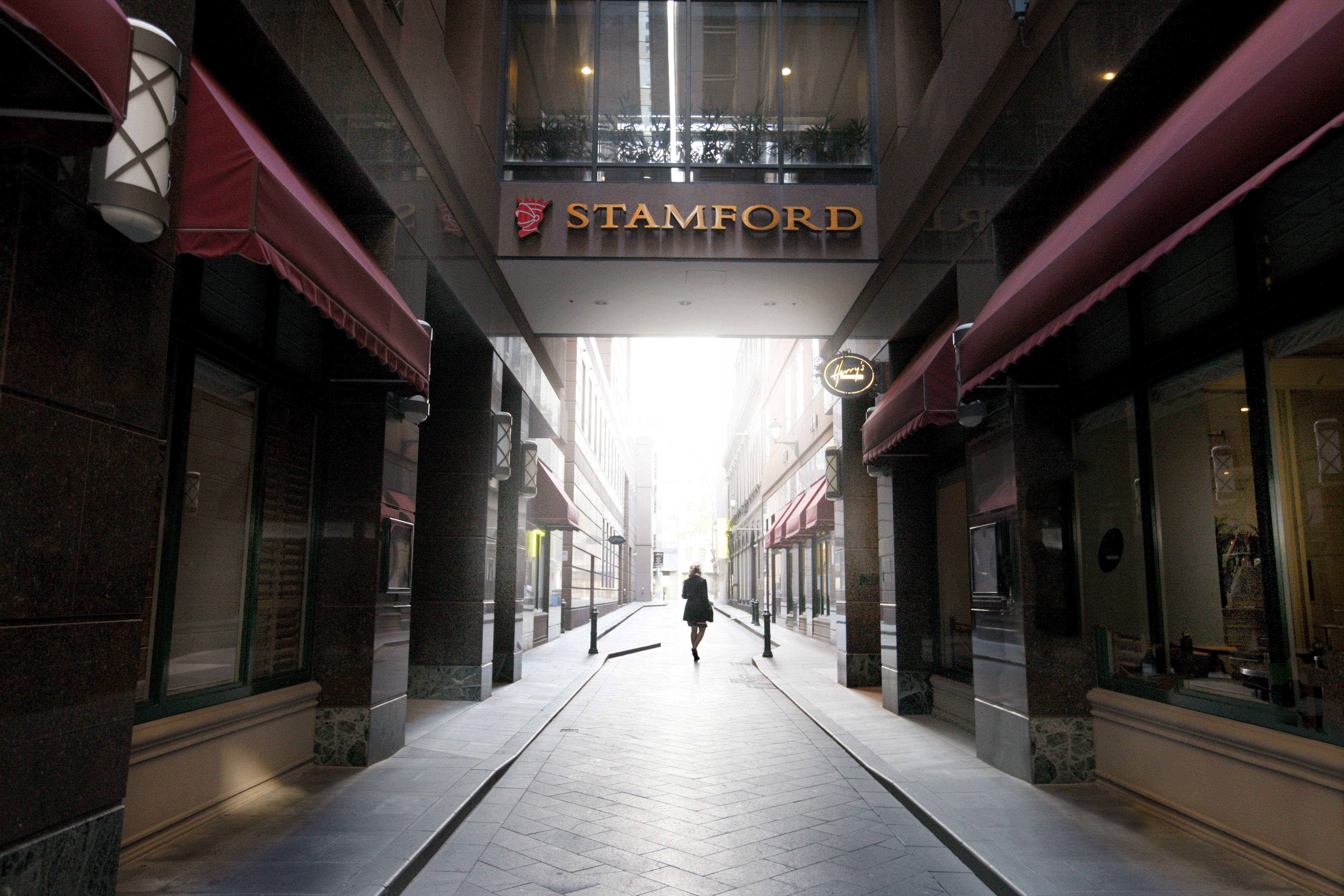 מלון Stamford Plaza מלבורן מראה חיצוני תמונה The photo depicts a narrow alley or passageway, possibly in an urban setting. On one side, there are storefronts with canopies, and on the opposite side, there is a prominent sign reading "STAMFORD." The pathway is lined with buildings, creating a se