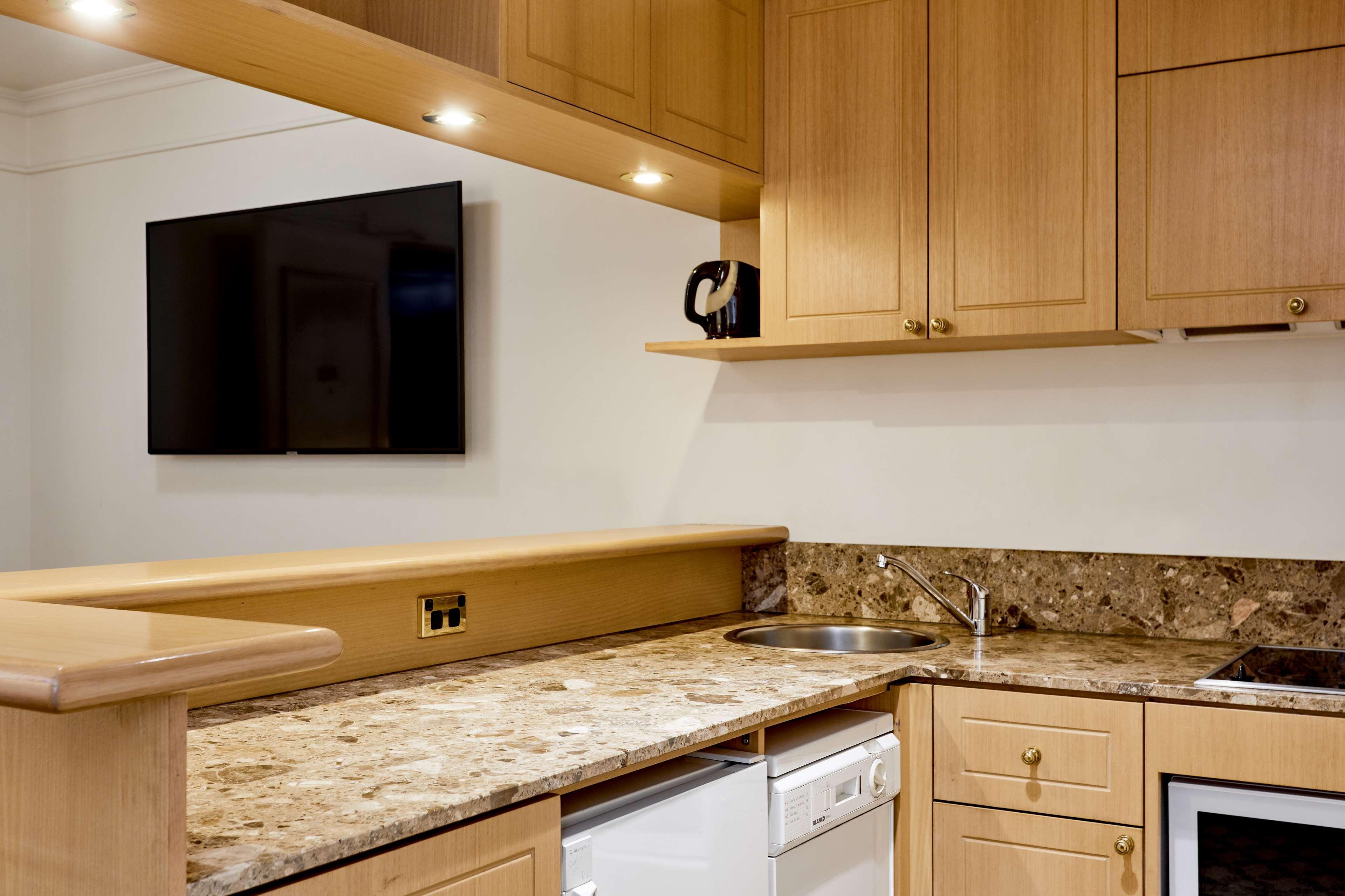 מלון Stamford Plaza מלבורן מראה חיצוני תמונה The photo shows a modern kitchen with wooden cabinetry and a granite countertop. There's a stainless steel sink integrated into the countertop, and appliances including a dishwasher and possibly a coffee maker on the shelf above. A flat-screen televi