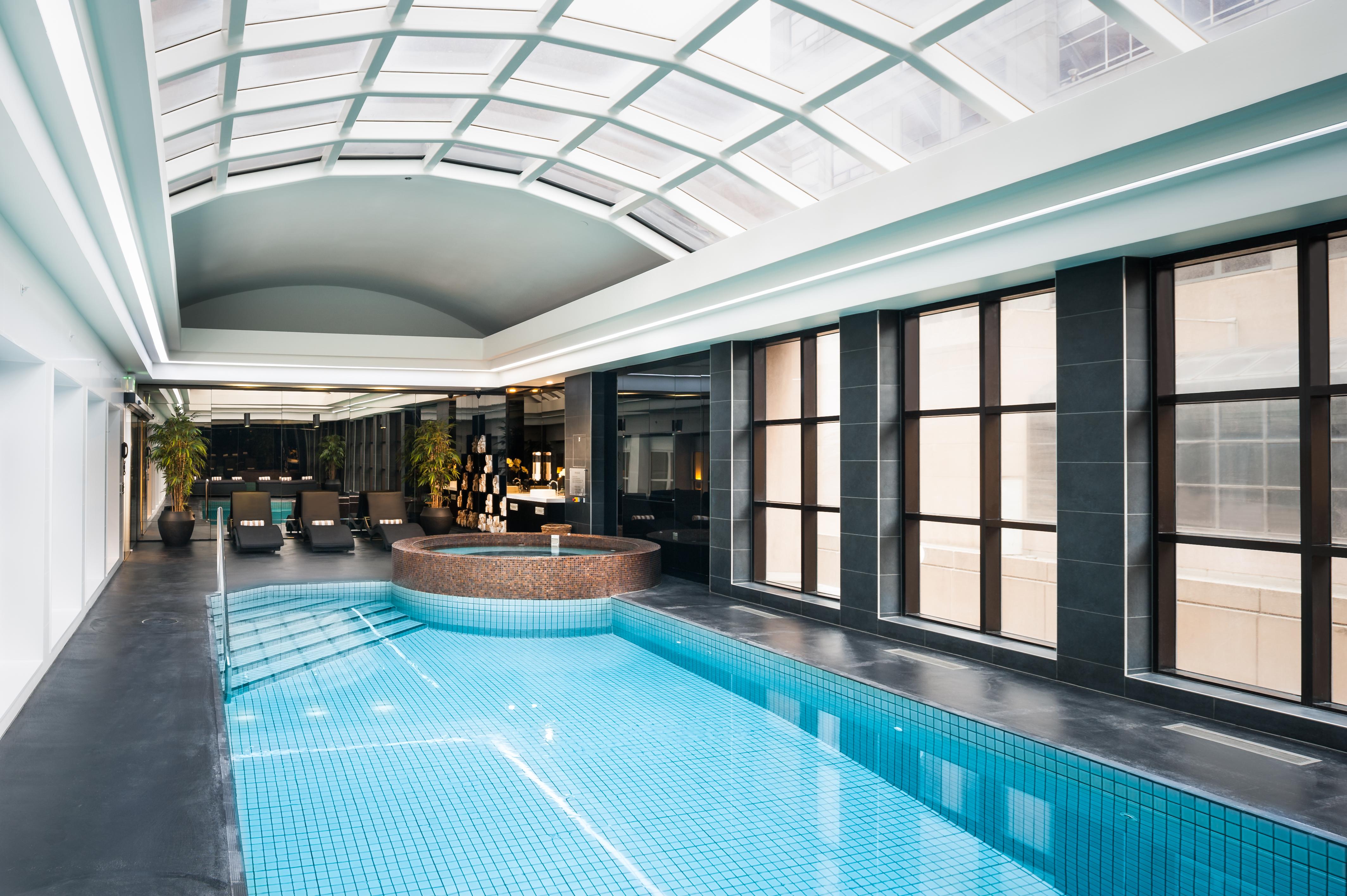 מלון Stamford Plaza מלבורן מראה חיצוני תמונה The photo shows an indoor swimming pool area with a modern and sleek design. The pool is rectangular and features bright blue tiles. Above the pool, there's a large, transparent glass ceiling that allows natural light to flood the space. Surrounding 