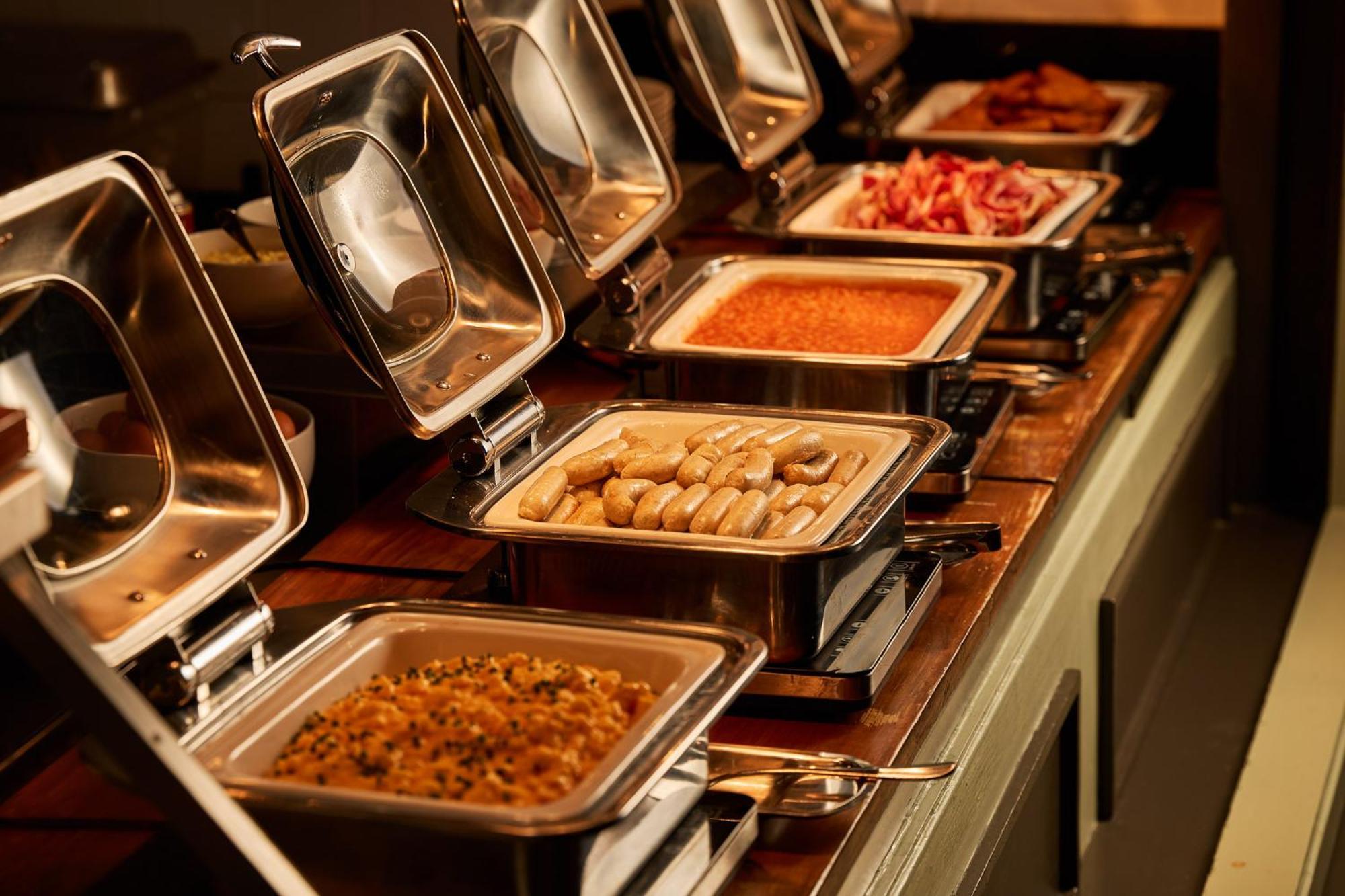 מלון Stamford Plaza מלבורן מראה חיצוני תמונה The photo depicts a buffet setup featuring multiple food trays in stainless steel chafing dishes. Each dish is opened to display different types of food. The dishes contain a variety of items, which might include a mix of proteins, vegetables, or sta