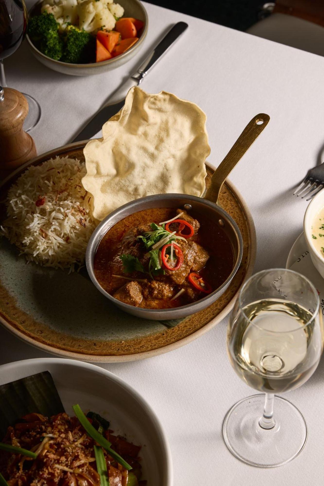 מלון Stamford Plaza מלבורן מראה חיצוני תמונה The photo features a plated meal that includes a serving of meat curry in a small round dish. The curry is garnished with herbs and slices of chili. Accompanying the curry, there is a mound of fluffy rice, and a piece of crispy flatbread (poppadom) r