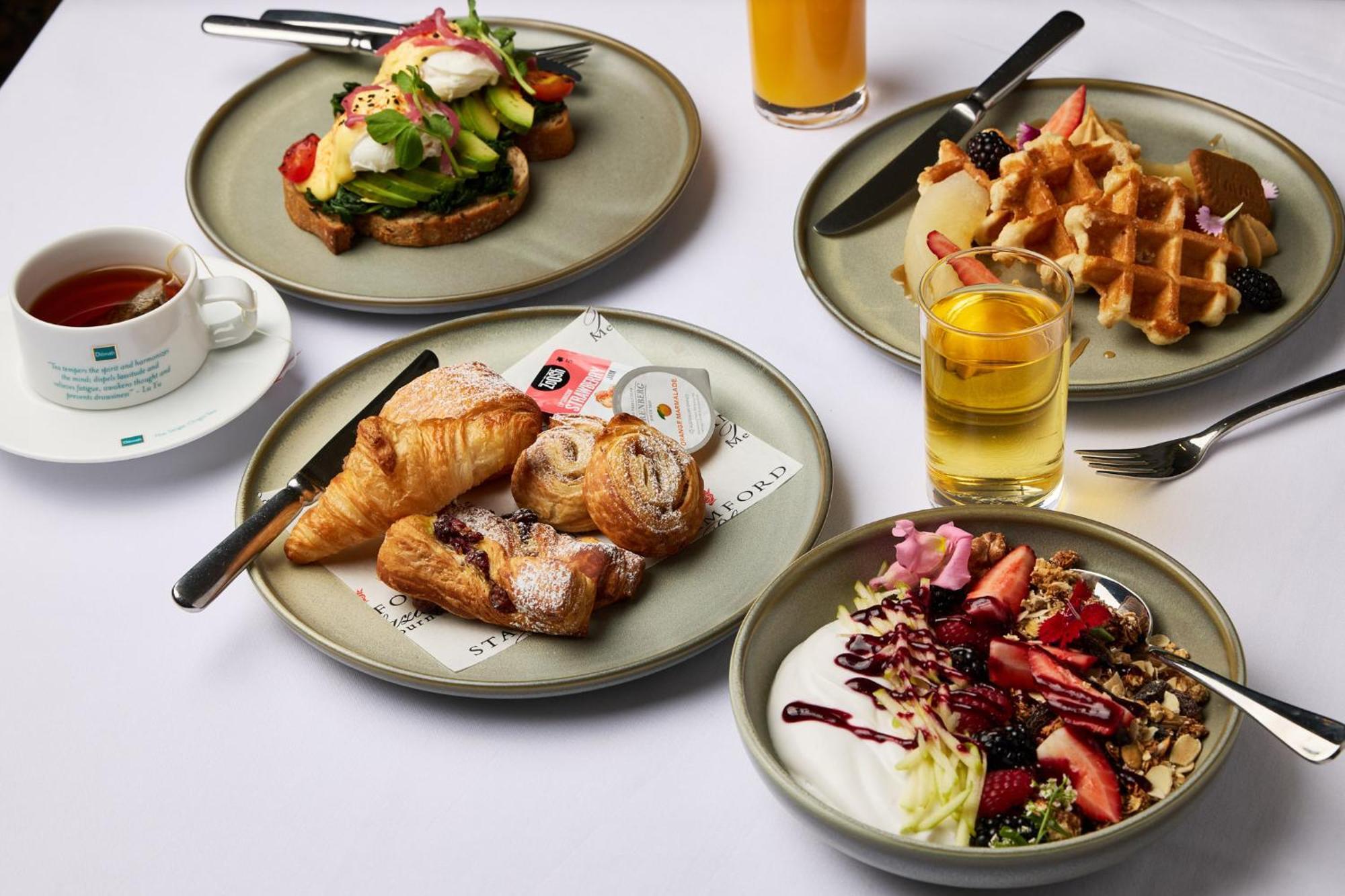 מלון Stamford Plaza מלבורן מראה חיצוני תמונה The photo displays a variety of breakfast items arranged on several plates. 

1. **Top-left Plate**: Features an open-faced sandwich with avocado, topped with poached eggs and garnished with vegetables.
2. **Top-right Plate**: Contains freshly made w