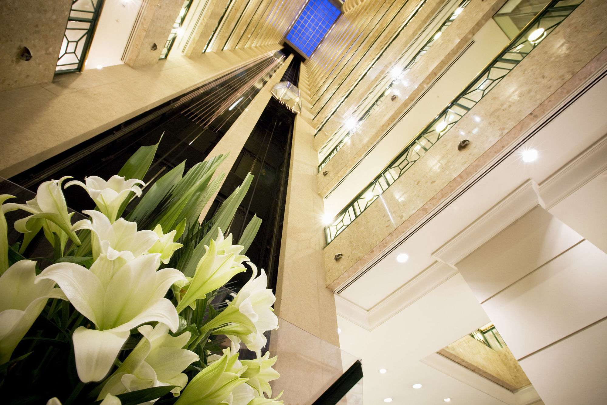 מלון Stamford Plaza מלבורן מראה פנימי תמונה The photo shows a modern indoor space, likely a lobby or atrium of a building. The view is looking upwards, capturing a sleek design with multiple levels. There are several elevators in the center, running vertically. The walls are lined with glass a